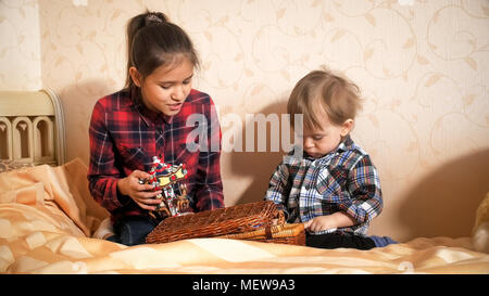 Teenage Mädchen spielen mit ihren Toddler Bruder auf dem Bett im Schlafzimmer Stockfoto