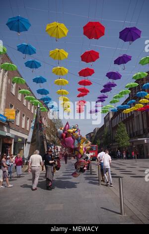 Ballon Verkäufer auf Exeter High Street mit der Exeter Rätsel Obelisk Skulptur und farbenfrohen Frühling Sonnenschirme. Devon, UK. April, 2018. Stockfoto