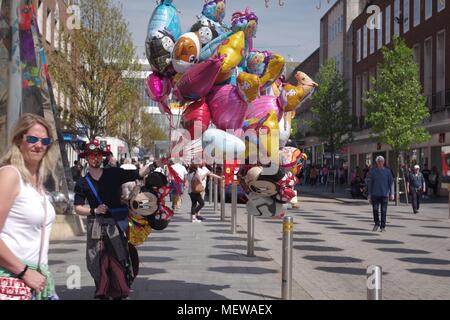 Ballon Verkäufer auf Exeter High Street mit der Exeter Rätsel Obelisk Skulptur und farbenfrohen Frühling Sonnenschirme. Devon, UK. April, 2018. Stockfoto