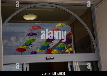 Reflexion der bunte Sonnenschirme in einem Schaufenster. Exeter Highstreet, Devon, Großbritannien. April, 2018. Stockfoto