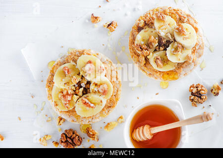Knäckebrot Banane und Erdnussbutter Snack. Gesundes Frühstück mit Walnüssen und Honig. High key Diät Konzept. Stockfoto