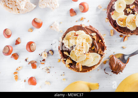 Knäckebrot Banane und Schokolade Snacks. Gesundes Frühstück mit Haselnüsse. High key Diät Konzept. Stockfoto