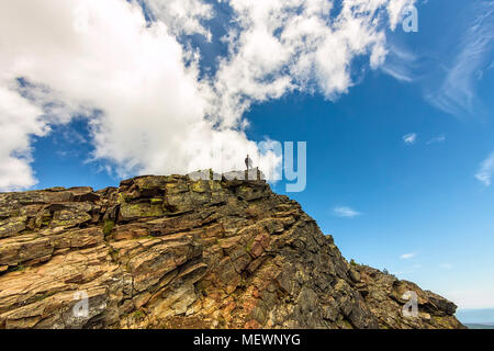 Man steht auf einem steilen Felsen auf dem Hintergrund der Himmel. Stockfoto