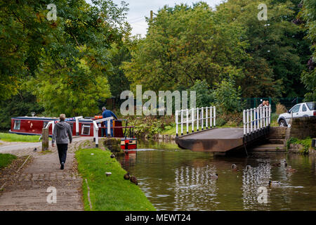 Gawflat Swing Brücke über den Leeds und Liverpool canal mit Wanderern, Touristen und schmalen Boot in Skipton, North Yorkshire, UK. Stockfoto