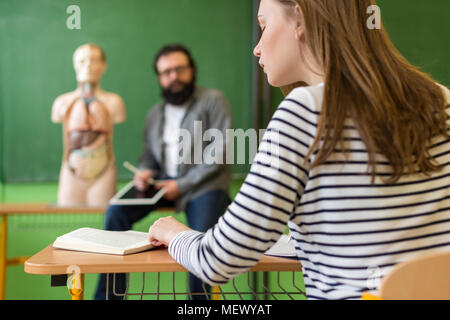 Junge männliche Hispanic Lehrer im Biologieunterricht, digital Tablet und Lehre menschlichen Körper Anatomie, mit künstlichen Körper Modell. Stockfoto