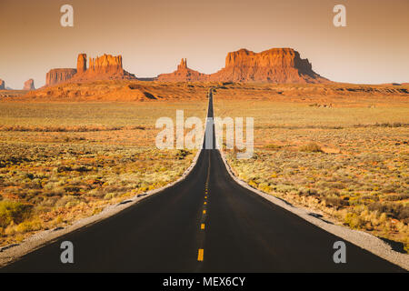 Classic Panorama der historischen U.S. Route 163, die durch die berühmten Monument Valley in wunderschönen goldenen Abendlicht bei Sonnenuntergang im Sommer, Utah Stockfoto