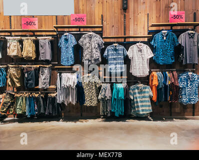 Jungen Abteilung in ein Bekleidungsgeschäft. Shop von Herrenbekleidung. Showcase Rack mit Hemden. Regale mit Kleidung. Der Innenraum des Store mit Kleidung. Kleidung auf Kleiderbügeln hängen in einer Boutique Stockfoto