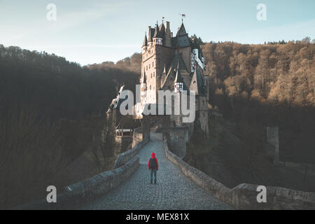 Panorama der jungen Entdecker mit Rucksack im Blick auf berühmte Burg Eltz bei Sonnenaufgang im Herbst, Rheinland-Pfalz, Deutschland Stockfoto