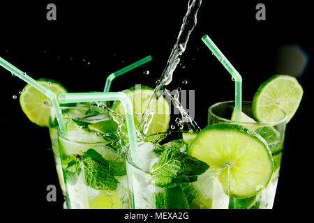 Gießen frischen Mojito Cocktail in Gläser auf schwarzem Hintergrund isoliert Stockfoto