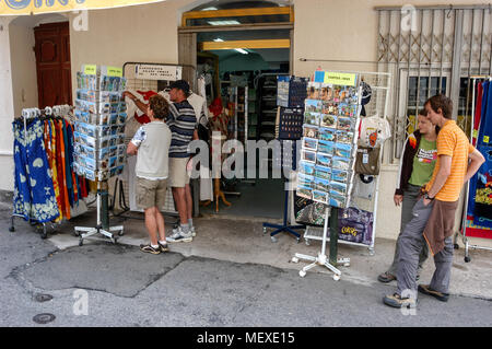 Touristen, die auf der Suche an einem Baugruppenträger oat ein Geschenk Shop in einer schmalen Straße, die Rue Georges Clemenceau in der alten Stadt, Calvi auf Korsika, einer französischen Insel im Sou Stockfoto