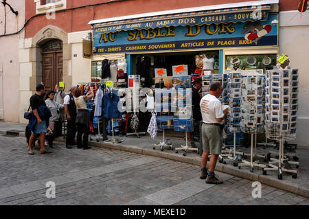 Touristen, die auf der Suche an einem Baugruppenträger oat ein Geschenk Shop in einer schmalen Straße, die Rue Georges Clemenceau in der alten Stadt, Calvi auf Korsika, einer französischen Insel im Sou Stockfoto