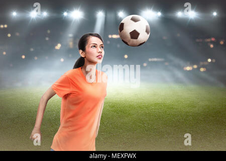 Jungen asiatischen Fußball-Spieler eine Frau an der Spitze der Kugel auf dem Feld Stockfoto