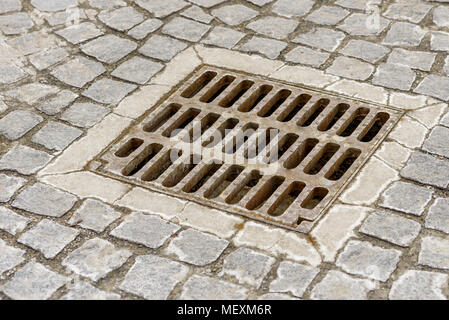 Kanalisation Rost für Regenwasser in der Nähe der Straße installiert und durch Kopfsteinpflaster umgeben Stockfoto