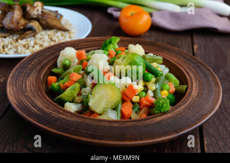 Gedünsteter Sommer Gemüse (Broccoli, Mais, Spargel, Rosenkohl, Karotten) in einem Ton Schüssel. Licht vegane Ernährung garnieren. Stockfoto