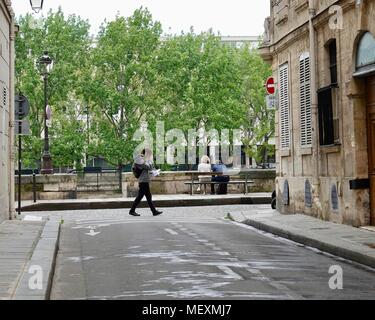 Paar sitzt auf der Bank entlang der Seine, während Mann hinter Ihnen, lesen sollt ihr eine Garbe der Papiere. Ile Saint-Louis, Paris, Frankreich. Stockfoto