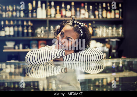 Lächelnden jungen afrikanischen cafe Eigentümer tief in Gedanken, während sich auf der Zähler von ihr angesagten Cafes Stockfoto