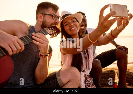 Lächelnd Freunde fotografieren mit verrückten Musiker am Strand. Stockfoto