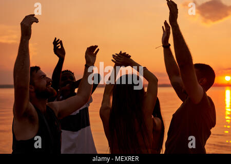 Ekstatisch junge Studenten genießen Beach Party bei Sonnenuntergang Stockfoto