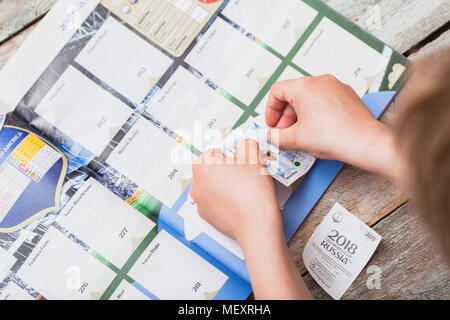BERLIN, DEUTSCHLAND - 20. APRIL 2018: sieben Jahre alten Jungen Aufkleber einfügen in die Panini Sammlung Album für die Fußball-Weltmeisterschaft in R Stockfoto