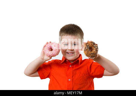 Wenig glücklich cute Boy ist Essen Donut auf whte Hintergrund Wand. Kind hat Spaß mit Donut. Leckeres Essen für Kinder. Lustige Zeit zu Hause mit süßen Speisen. Helle Kid. Stockfoto