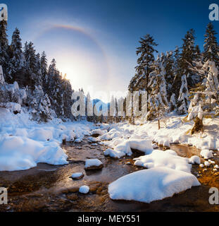 Erstaunlich Frühling Landschaft. Mountain Stream in Tatra Berge mit schneebedeckten Riverside. Halo Effekt in blue Clear Sky. Stockfoto