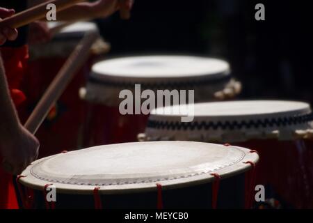 Nahaufnahme von Taiko Drum Felle, geschlagen mit Bachi Sticks. Auf der RAMM Karneval der Tiere, Rougemont Gärten, Exeter, Devon, Großbritannien. April, 2018. Stockfoto