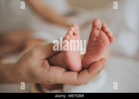 Mutter halten Sie die Füße des neugeborenen Babys. Hautpflege. Stockfoto