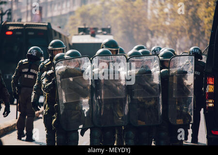 Santiago, Chile - 19. April 2018: eine Linie der chilenischen Polizei beobachten Demonstranten während einer Demonstration in der Innenstadt von Santiago, Chile. Die Demonstranten Stockfoto