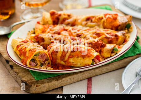 Enchiladas mit Reis, gekochter Schinken, grüne und rote Paprika in Tomatensauce und Käse Stockfoto