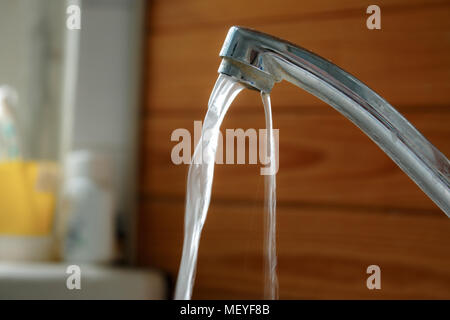 Das Wasser fließt von den schmutzigen Gebrochenen Aluminium Wasserhahn im Bad. Stockfoto