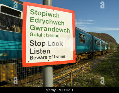 Warnschild auf einem Wanderweg, der über eine Bahnstrecke mit einem nahverkehrszug vorbei Stockfoto