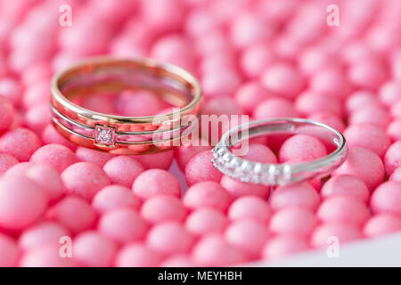 Gelbe und weiße Gold Wedding Ring mit Diamant. rosa Kugeln und Blasen Hintergrund. Original Fach für die Zeremonie der Ehe. Stockfoto