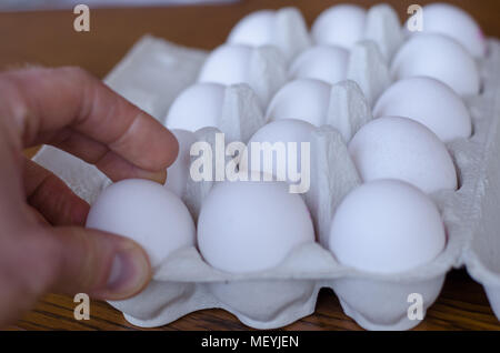 Ein Ei unter einer Gruppe von Eiern, die von einer Hand abgeholt werden Stockfoto