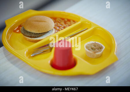 Eine Schule Abendessen Fach mit Burger, Bohnen, Kuchen und Getränken Stockfoto