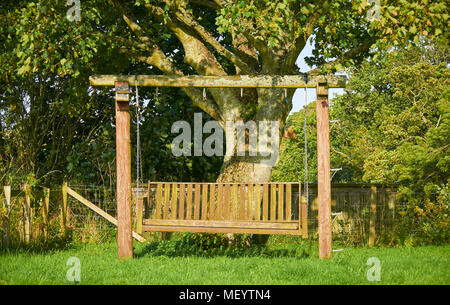 Einen hängenden Garten Sitzbank steht unter den Platanen der Bauerngarten im Colliston, Angus in Schottland leer. Stockfoto