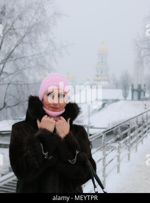 Die Nahaufnahme der lächelnden und wohlhabenden Frau im Pelzmantel und goldene Ringe an der snow-covered Bridge. Winter portrait. Stockfoto