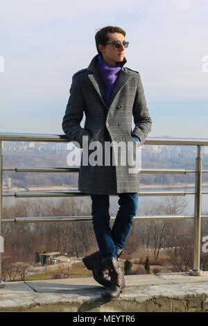 Das Porträt einer schönen jungen Hipster in die schwarze Sonnenbrille, die auf der linken Seite ein auf der Brücke stehen in einem Park auf der Suche ist. Sonniges Wetter. Stockfoto