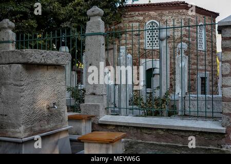 Foto eines dem Außenbereich der Kleine Hagia Sophia, einen Brunnen außerhalb der Metall Zaun, der Marmor Friedhof Stücke in der Moschee yard schützt, und die byzantinischen Mauer Fassade Fassade der Moschee, die früher die Kirche der Heiligen Sergius und Bacchus, in Istanbul, Türkei, 10. November 2017. () Stockfoto