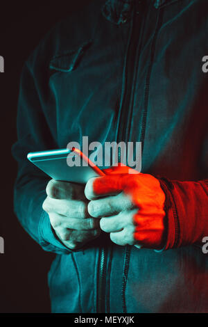 Mann mit Handy, blau und rot beleuchtet Low Key Close up Beschnittenes Bild der männlichen Händen mit Smartphone Stockfoto
