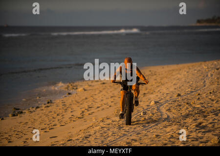 Ein Mann reitet ein Fett Fahrrad entlang dem Strand von Saint-Gilles am Indischen Ozean Insel La Reunion. Stockfoto