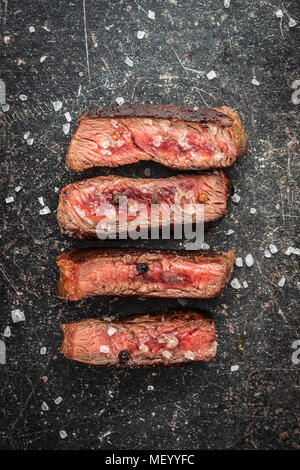 In Scheiben geschnitten medium gegrilltes Steak auf alten Küchentisch. Stockfoto