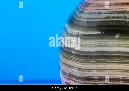 Makro Foto Textur aus poliertem onyx Stein auf einem blauen Hintergrund. Fotos für die Website über Geologie, Steine, Schmuck, Handarbeit, Texturen, Kunst, Astronomie. Stockfoto