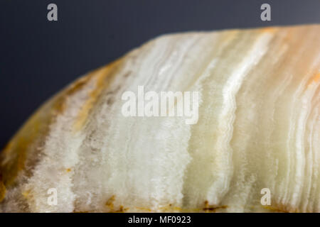 Makro Foto Textur aus poliertem onyx Stein auf einem grauen Hintergrund. Fotos für die Website über Geologie, Steine, Schmuck, Handarbeit, Texturen, Kunst, Astronomie. Stockfoto