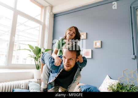 Gerne Vater mit Sohn huckepack zu Hause Stockfoto