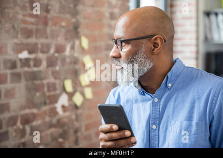 Geschäftsmann mit Mobiltelefon in einem Loft Stockfoto