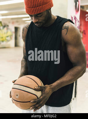 Mann mit Tattoos und Wollmütze holding Basketball Stockfoto