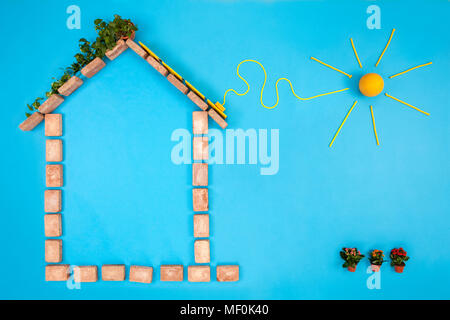 Haus Form aus Ziegel auf blauem Hintergrund, mit Solar Panels angeschlossen an Sun Stockfoto
