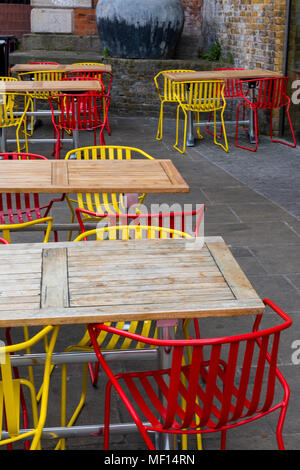 Gelb und Rot leuchtend bunten Tische und Stühle in einem Café oder Restaurant durch die Seite der Themse im Zentrum von London Trendy modische Cafe. Stockfoto