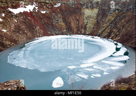 Winter Farben der wunderschönen Kerio oder Krater Kerid in Island. Roten Vulkangestein, Grün bemoosten Pisten und ein Kreis von Brechendem Eis in einem türkisfarbenen See Stockfoto