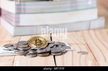 Bitscoin befindet sich auf der Oberseite der Münze auf den Tisch gelegt. Es gibt einen Stapel Bücher auf der Rückseite in finanziellen Konzepten. Stockfoto